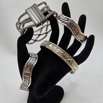 LOT 27: Three Silver-tone Cuff Bracelets and one Magnetic Closure Braided Rope-like Bracelet