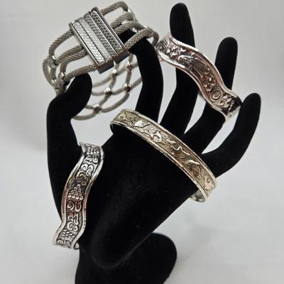 LOT 27: Three Silver-tone Cuff Bracelets and one Magnetic Closure Braided Rope-like Bracelet