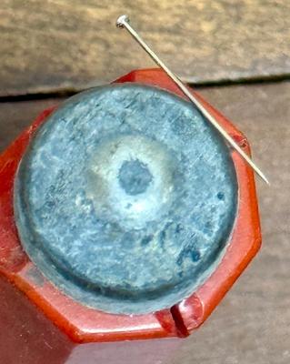 Sale Photo Thumbnail #381: Strong magnet for holding or pulling bobby pins, covered in what appears to be marbled red bakelite.    Bakelite is damaged, with a long split on one side a a section broken off near the magnetic tip.  Could also be used in sewing to hold straight pins.