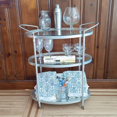LOT 25: Metal and Glass Serving Cart with Glasses, Shaker, Tablecloths, Corkcicle Wine Pourer, Whimsical Straws and More