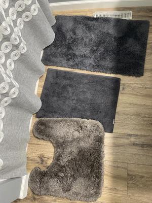 Gray shower curtain and three rugs