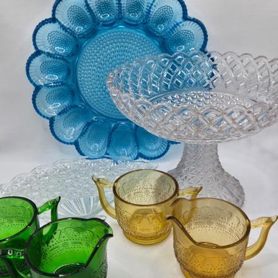 LOT 131: Blue Glass Deviled Egg Plate, Lace Edge Clear Glass Pedestal Bowl, Fan Plate, Green and Amber Glass Lace & Dew Drop Cream...