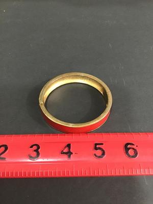 Gold tone hinged bracelet with red enamel