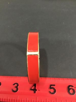 Gold tone hinged bracelet with red enamel