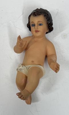 Sale Photo Thumbnail #72: Recling Statue made of hand-painted porcelain with varying flesh tones. It has glass eyes and open mouth.  Cradle has straw and blanket along with a gray scarf.