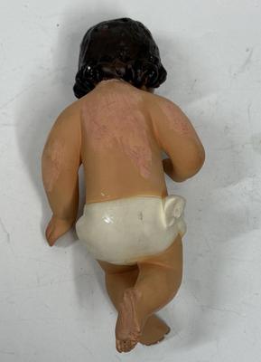 Sale Photo Thumbnail #66: Recling Statue made of hand-painted porcelain with varying flesh tones. It has glass eyes and open mouth.  Cradle has straw and blanket along with a gray scarf.