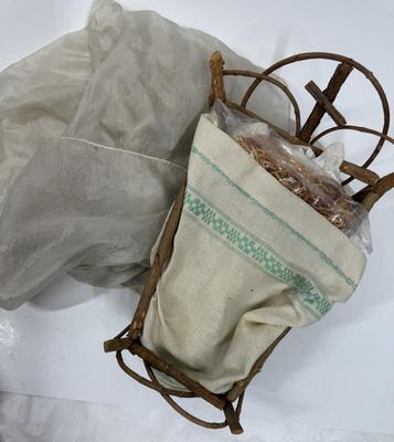 Sale Photo Thumbnail #63: Recling Statue made of hand-painted porcelain with varying flesh tones. It has glass eyes and open mouth.  Cradle has straw and blanket along with a gray scarf.