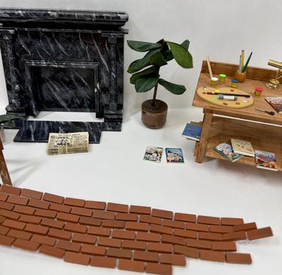 Sale Photo Thumbnail #332: Fireplace, 2 potted plants. brick patch, Miniaturized Disney Books, Miniaturized Disney Poster, Brass Light fixture on desk, scissors, brush, pencil, pain pallet, paint, chalk, crayons, newspapers etc
