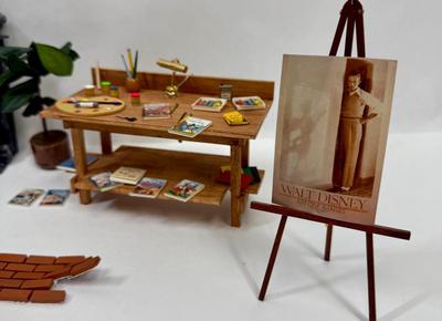Sale Photo Thumbnail #328: Fireplace, 2 potted plants. brick patch, Miniaturized Disney Books, Miniaturized Disney Poster, Brass Light fixture on desk, scissors, brush, pencil, pain pallet, paint, chalk, crayons, newspapers etc