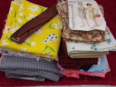 A pile of fabric in a box plus a dress pattern w/fabric & buttons,