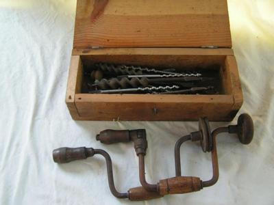 A pair of hand drill braces w/ a collection of drill bits in a wooden box.