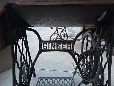 Sale Photo Thumbnail #782: Antique Singer Sewing Machine Table Plus Sewing Accoutrements (Lot of 4). Sewing machine with original table and foot pedal, cast iron and wood details. Also includes folding wooden box of different sewing feet, Singer buttonhole making foot, and pin cush