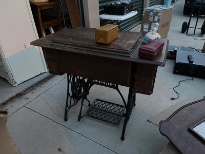 Sale Photo Thumbnail #781: Antique Singer Sewing Machine Table Plus Sewing Accoutrements (Lot of 4). Sewing machine with original table and foot pedal, cast iron and wood details. Also includes folding wooden box of different sewing feet, Singer buttonhole making foot, and pin cush