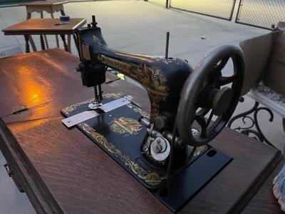 Sale Photo Thumbnail #786: Antique Singer Sewing Machine Table Plus Sewing Accoutrements (Lot of 4). Sewing machine with original table and foot pedal, cast iron and wood details. Also includes folding wooden box of different sewing feet, Singer buttonhole making foot, and pin cush