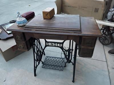 Sale Photo Thumbnail #780: Antique Singer Sewing Machine Table Plus Sewing Accoutrements (Lot of 4). Sewing machine with original table and foot pedal, cast iron and wood details. Also includes folding wooden box of different sewing feet, Singer buttonhole making foot, and pin cush