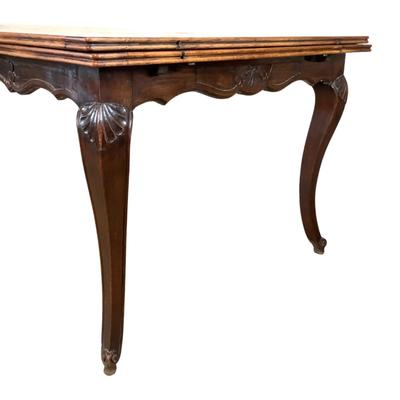Sale Photo Thumbnail #237: Solid oak table with a burl wood top adding a rich warm patina that speaks to its age and quality. The table boasts intricate carvings along its edges and legs, showcasing the craftsmanship of the period. Its extendable design allows for versatile seating