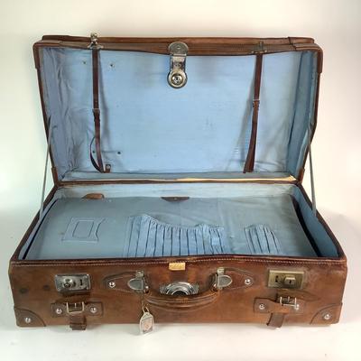 Sale Photo Thumbnail #282: Reinforced exposed straps, handles, chrome latches, includes working key, original pale blue textile interior, one ripped strapped everything else leather is intact. Rich dark leather patina. 30" wide x 11.5" high x 17" deep.