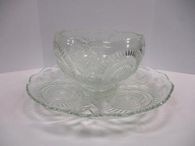 Sale Photo Thumbnail #395: The product is an antique EAPG (Early American Pattern Glass) punch bowl and underplate made by the U.S. Glass Co. The intricate design features a slanted horseshoe and radial daisy pattern, adding a touch of elegance to any dining or kitchen decor. The g
