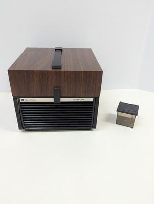 Sale Photo Thumbnail #1951: The Bell & Howell Slide Cube Projector Model 981Q is a high-quality slide projector designed by the well-known brand Bell and Howell. Featuring a unique cube design, this model allows for easy slide transitions and provides a clear and vibrant projection.