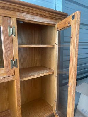 Sale Photo Thumbnail #898: Tall Wooden Hutch with Glass Inserts. Glass is removable, doors have magnetic closures. Plus an extra pull out serving surface. Huge amount of storage. Some sun bleaching on the upper cabinets and missing some of the magnetic closures, but otherwise good 