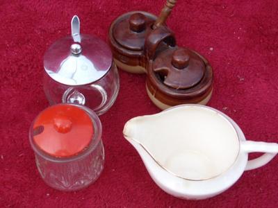 A group of sugar bowls and a creamer.