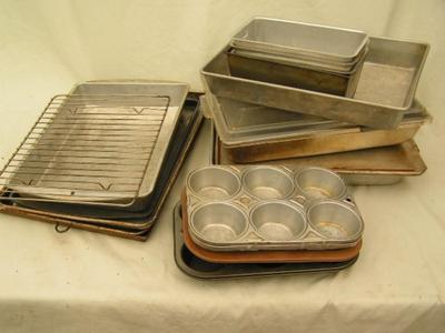 A box full of baking pans, baking sheets, cupcake pans, and more