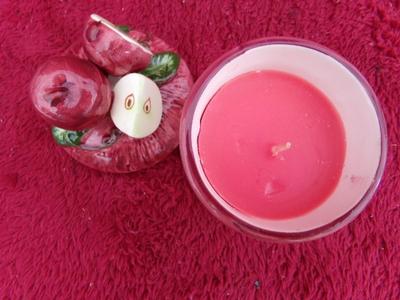 A candle in a ceramic jar. Apples on lid & side of jar. NEW IN BOX