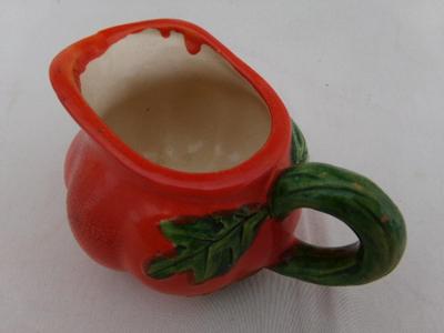 A tiny creamer sized pitcher, looks like a tomato and about thst size