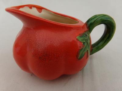 A tiny creamer sized pitcher, looks like a tomato and about thst size