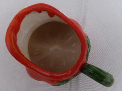 A tiny creamer sized pitcher, looks like a tomato and about thst size