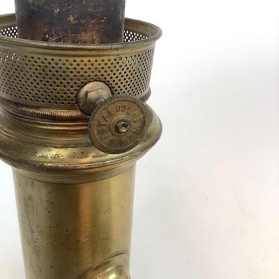 Sale Photo Thumbnail #1310: This is an old, heavy brass oil lamp made by Miller. It has a tarnished brass finish and a turnable body. The glass globe is an Aladdin brand and has a small chip on the bottom that's hidden when attached. The word "Miller" is stamped on the bottom and "E
