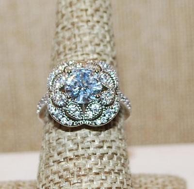 Size 7¼ Single Clear Main Stone Ring Surrounded by Brillance Small Stones on a Silver Tone Band (5.1g)