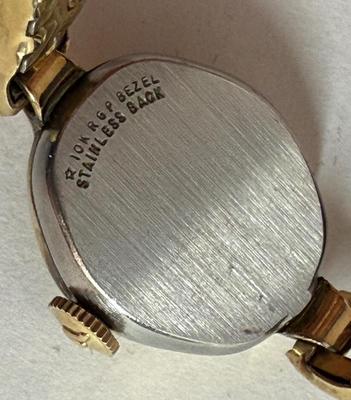 Sale Photo Thumbnail #74: Manual wind, in running condition. With a stretch-style band.  Round white watch dial. Swiss-made, 10K Rolled Gold Plate Bezel.