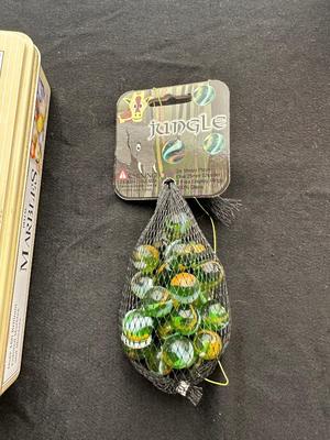 UNOPENED JUNGLE BAG AND A TIN OF MISC MARBLES