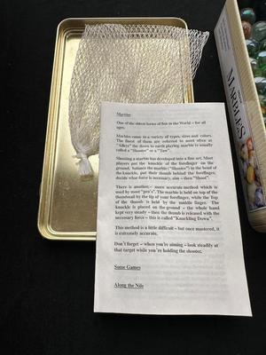 UNOPENED JUNGLE BAG AND A TIN OF MISC MARBLES