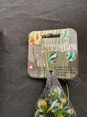 UNOPENED JUNGLE BAG AND A TIN OF MISC MARBLES