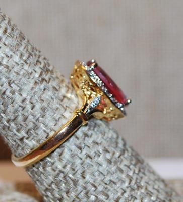 Size 8¼ Light Red Oval Cut Transparent Stone Ring with Full Clear Stones Surround and Side Accents on a Gold Tone Band (3.3g)