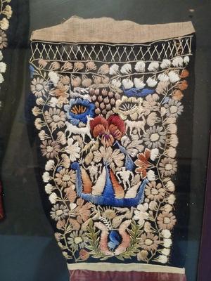 Sale Photo Thumbnail #301: Embroidery includes flowers, leaves, vines, people, animals, birds/peacocks Frame, 19 3/8" x 26", Sleeves approx. 6 1/2" x 13".