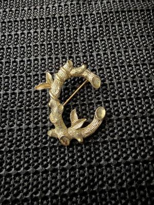 vintage Sarah Coventry gold-tone initial "C" brooch featuring a tree branch and leaf design.