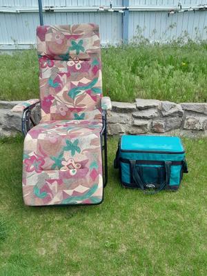 Folding metal framed cushioned chair and a cooler.