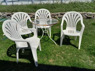 Small glass topped table with 4 plastic patio chairs