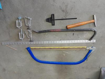Bow saw, Claw bar, metal yard stick / ruler, and a tack hammer.