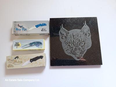 Laser art tile of a bobcat and three new pocketknives