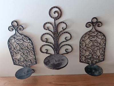 Three metal candle sconces with elegant votive candles