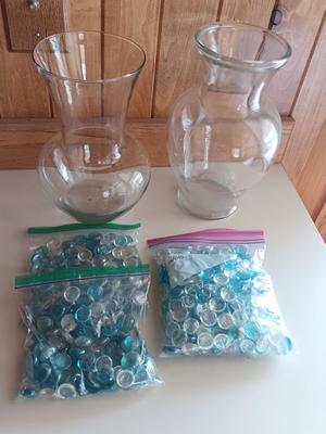 Two tall clear vases with blue toned and clear glass pebbles