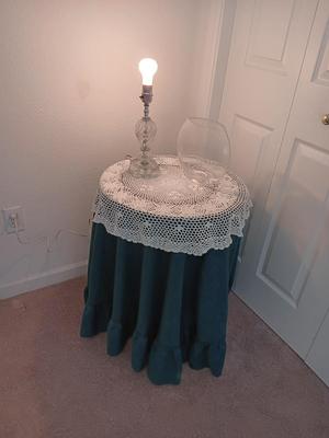 Small covered accent table with vintage lamp and glass vase
