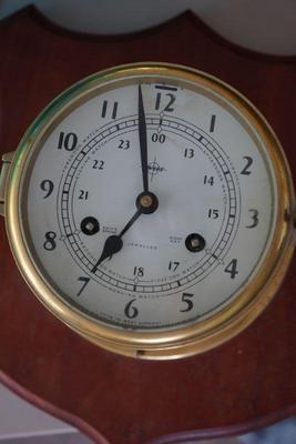 Key wind porthole clock mounted on board. 