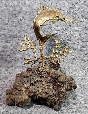 Brass swordfish sculpture on rock
