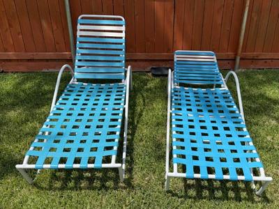Two blue and white reclining patio chairs