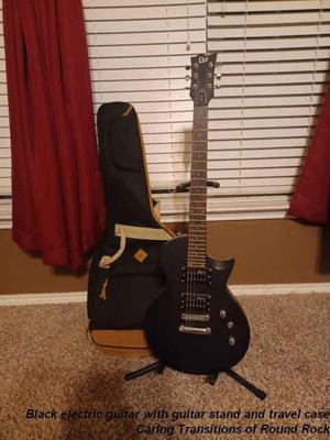 Black electric guitar with guitar stand and travel case